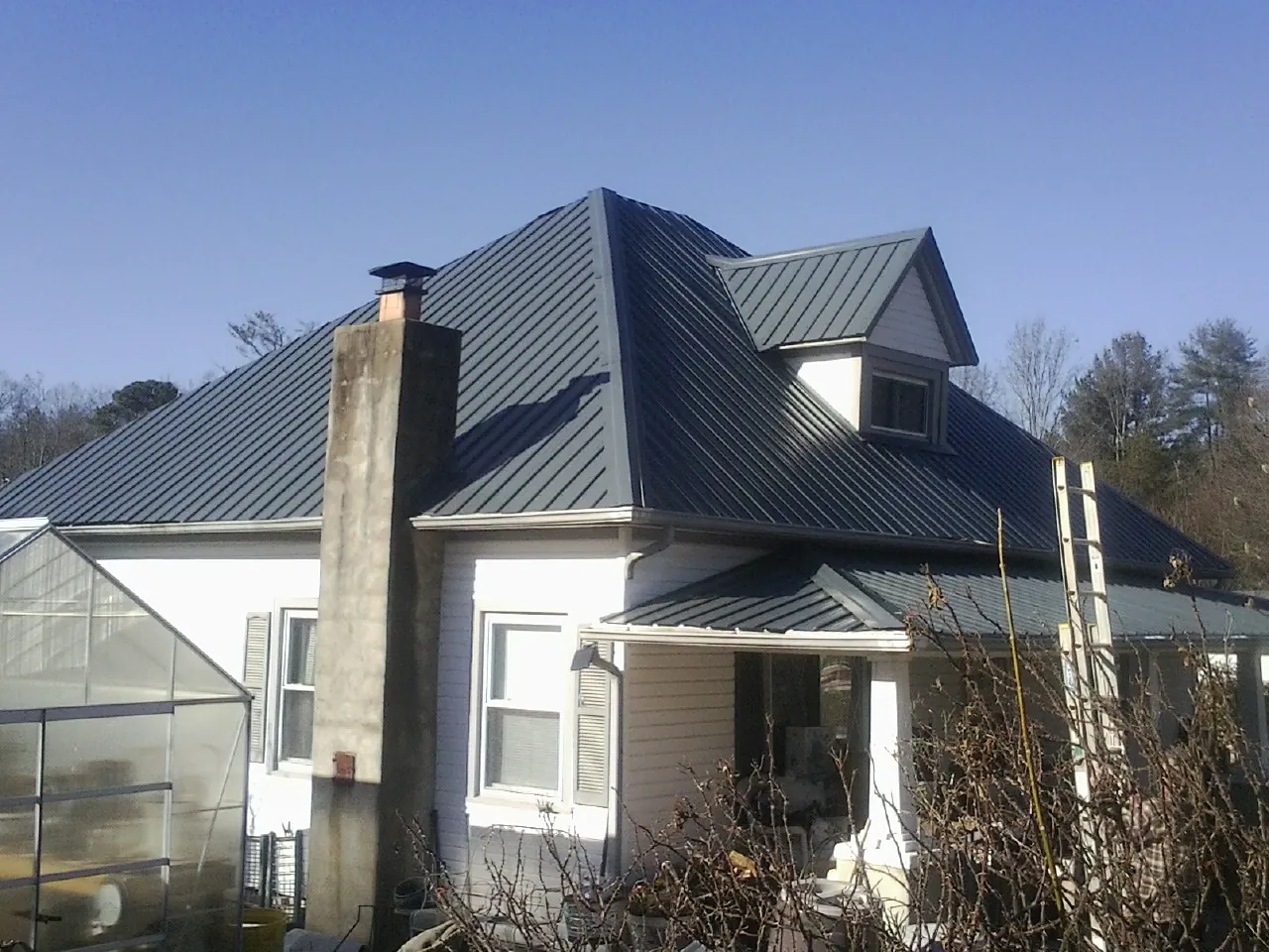 Dark blue standing seam metal roof on a white farmhouse with dormer — Slate & Tile Roof Repair by Roofing Brothers in Trappe