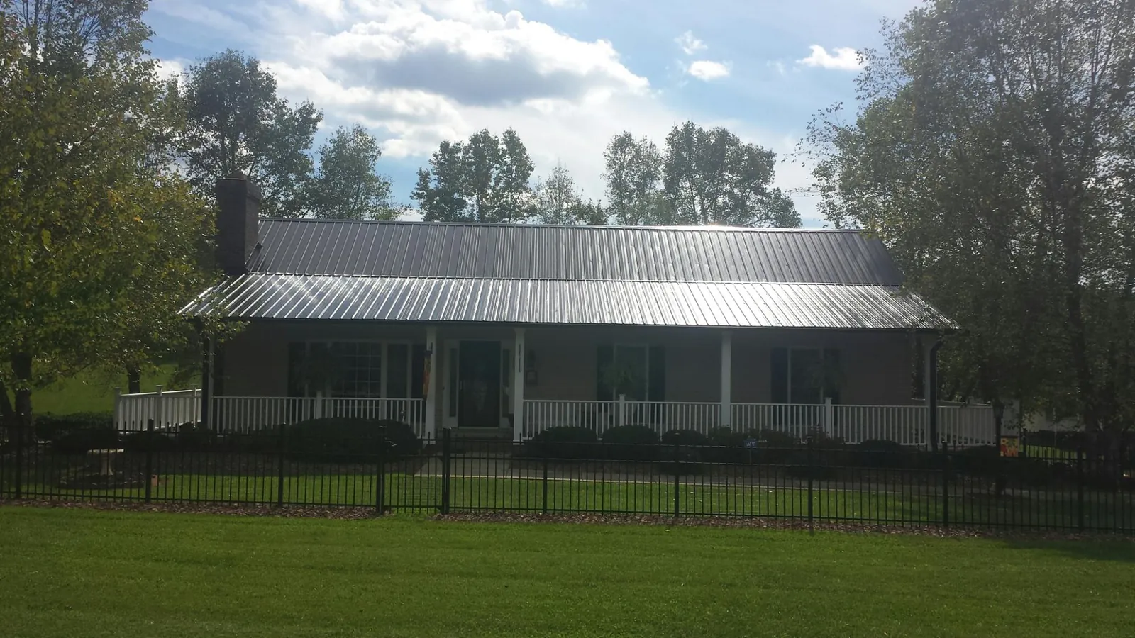 Gray metal roof on a brick ranch with a full width front porch — Gutter Guard Installation work by our crew in Trappe
