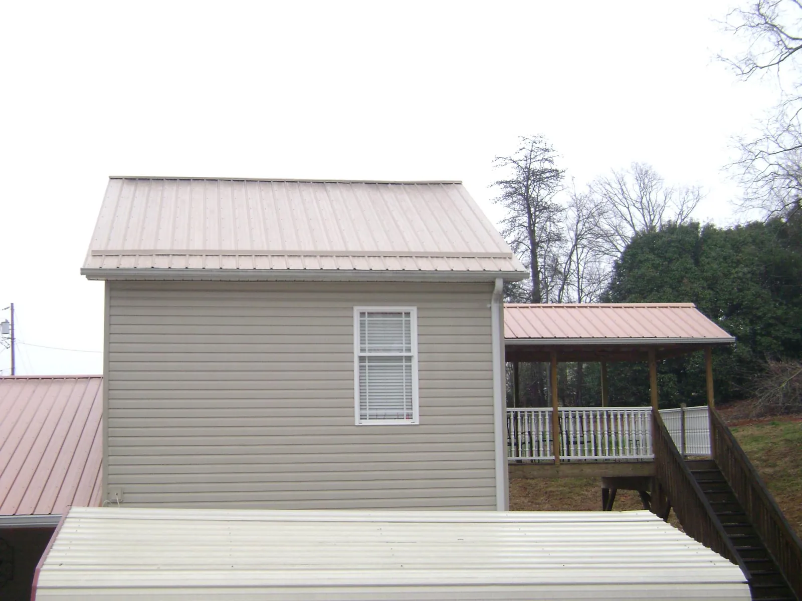 Tan metal roofs on a two story addition and attached porch, from a Roof Replacement job in Trappe