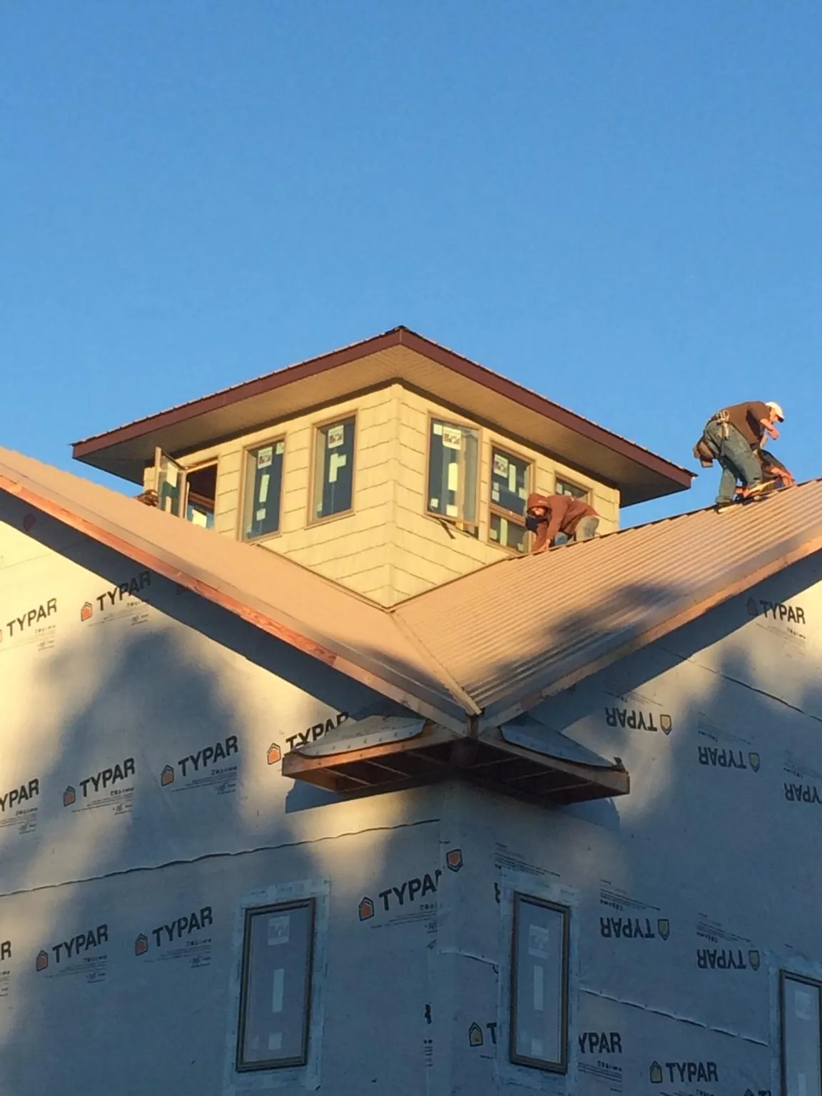 Roofers working around a rooftop cupola on a new metal roof at sunset — Roof Waterproofing in Trappe by Roofing Brothers